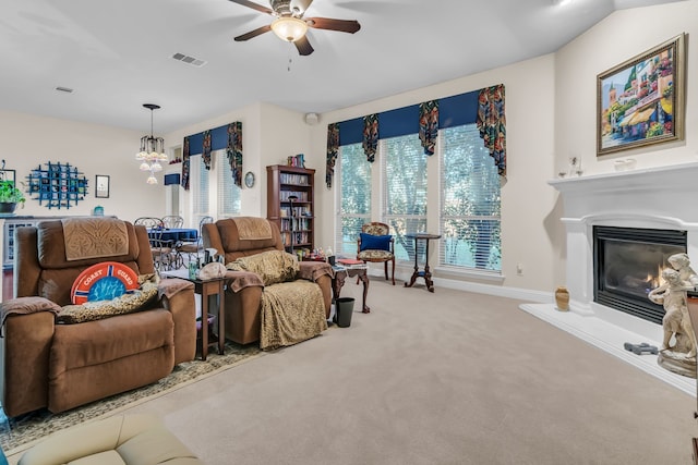 carpeted living room with ceiling fan with notable chandelier