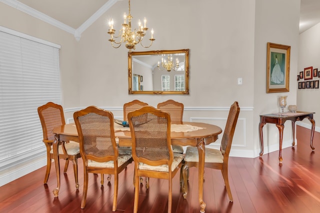 dining area featuring hardwood / wood-style flooring, vaulted ceiling, ornamental molding, and an inviting chandelier