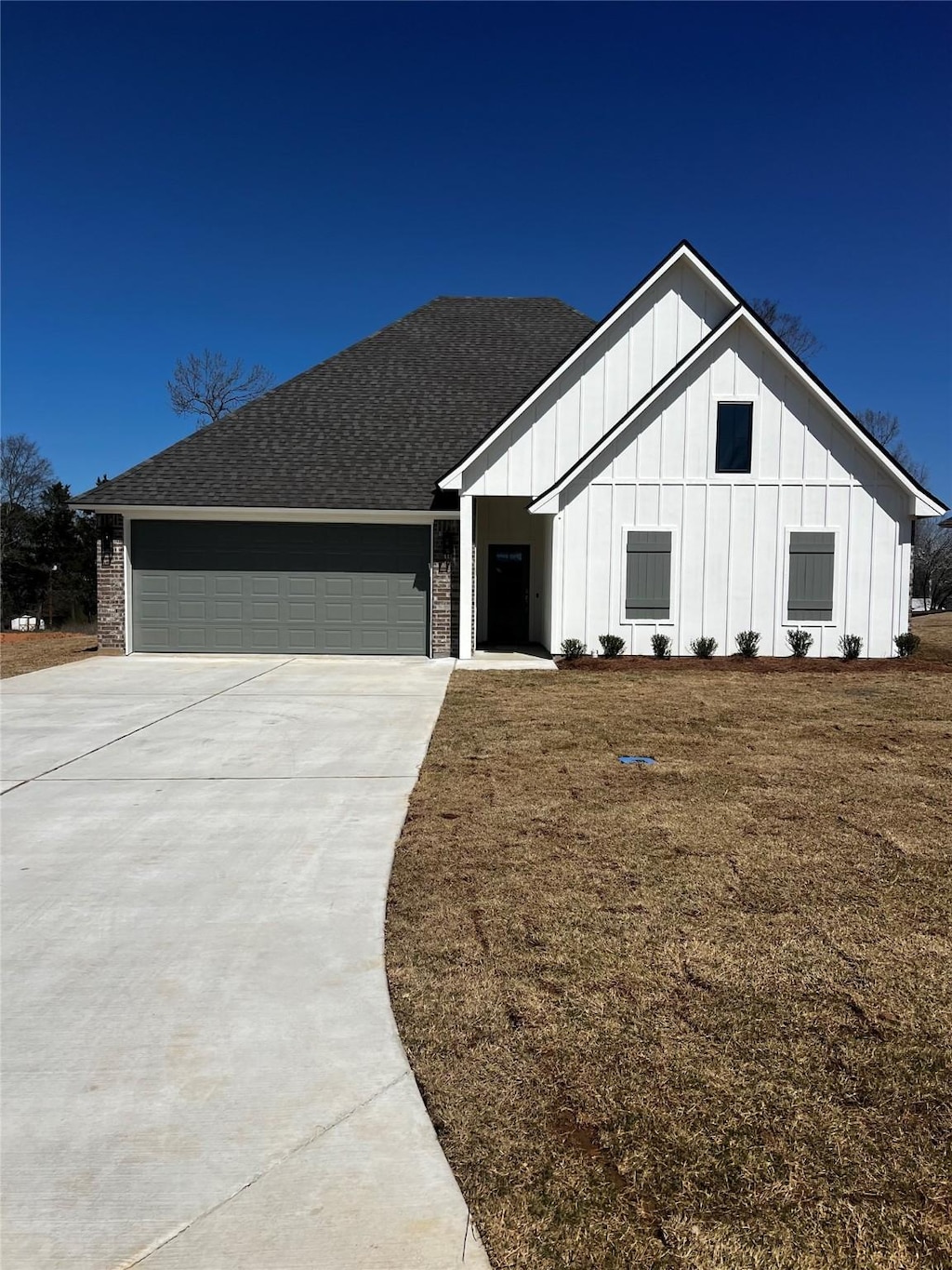 modern farmhouse style home with board and batten siding, concrete driveway, an attached garage, roof with shingles, and brick siding