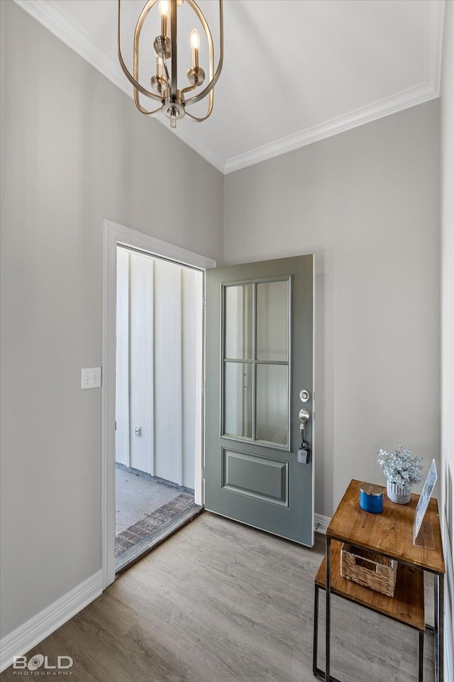 entryway featuring baseboards, an inviting chandelier, wood finished floors, and crown molding