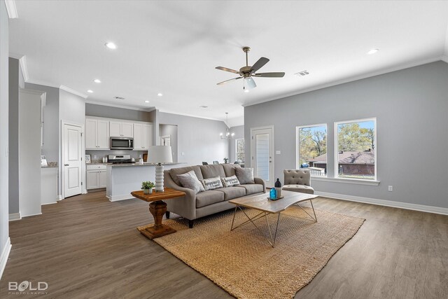 living area with visible vents, baseboards, wood finished floors, and ceiling fan with notable chandelier
