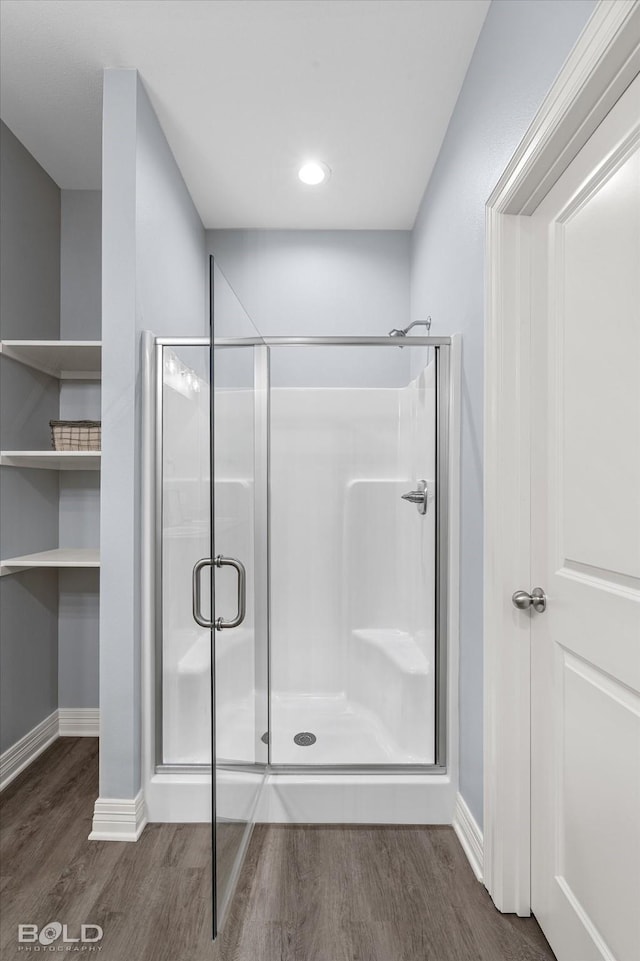 bathroom featuring baseboards, wood finished floors, and a shower stall