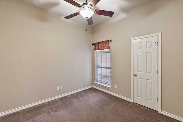 spare room featuring ceiling fan and dark carpet