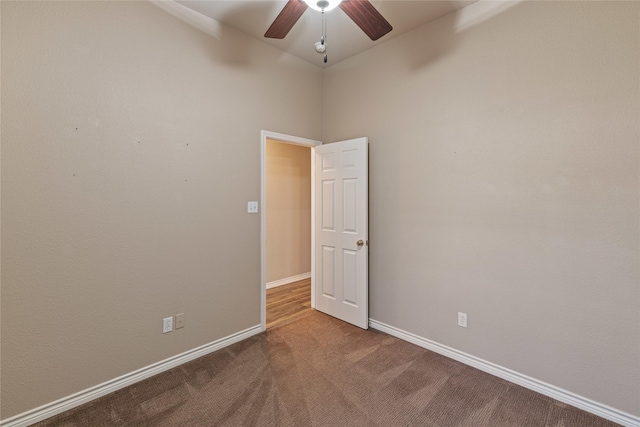 carpeted spare room with ceiling fan and a high ceiling