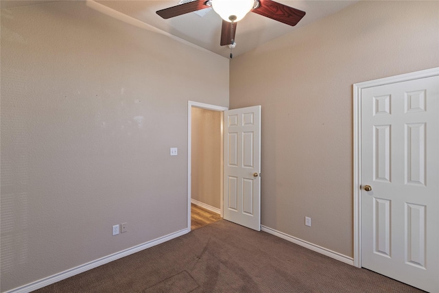 unfurnished bedroom with ceiling fan and dark carpet