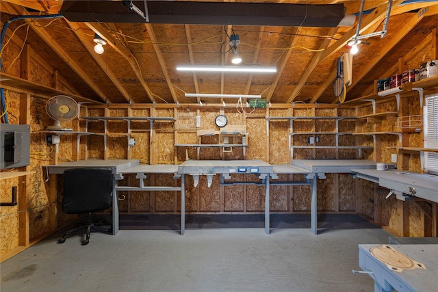 interior space with electric panel, concrete floors, vaulted ceiling, and a workshop area