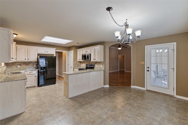 kitchen with appliances with stainless steel finishes, backsplash, hanging light fixtures, light stone countertops, and sink