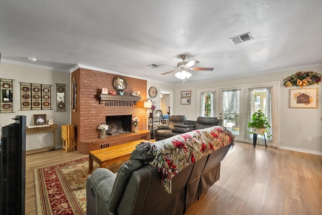 living room with a textured ceiling, crown molding, a fireplace, and light wood-type flooring