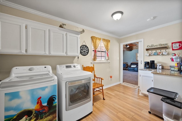 washroom featuring cabinets, washing machine and dryer, crown molding, and light hardwood / wood-style floors