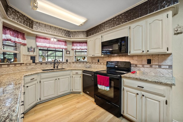 kitchen featuring light hardwood / wood-style floors, black appliances, light stone countertops, crown molding, and sink