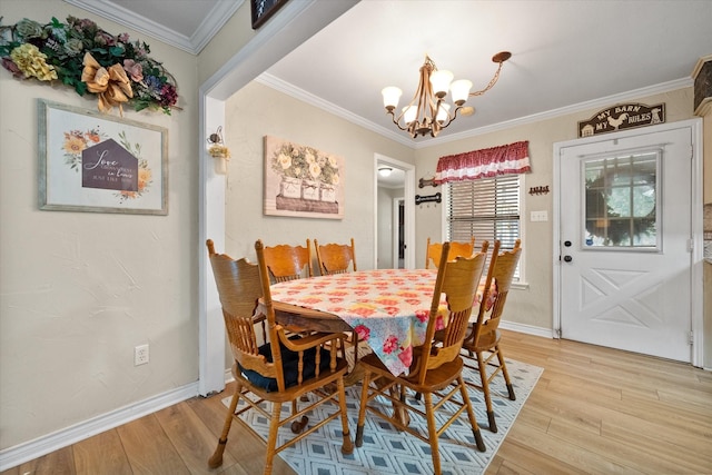 dining room with ornamental molding, baseboards, light wood finished floors, and an inviting chandelier