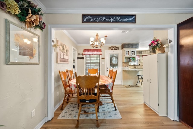 dining space featuring visible vents, crown molding, light wood finished floors, and an inviting chandelier