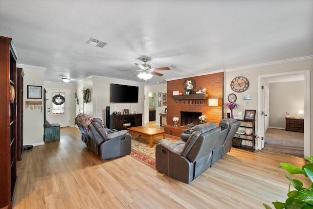 living area featuring light wood-type flooring, a fireplace, visible vents, and ornamental molding