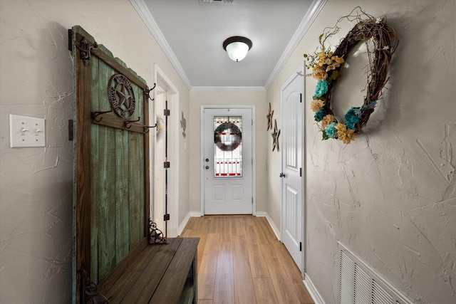 doorway with baseboards, light wood-style flooring, visible vents, and crown molding