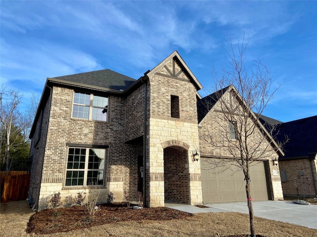 view of front of property with brick siding, roof with shingles, an attached garage, stone siding, and driveway