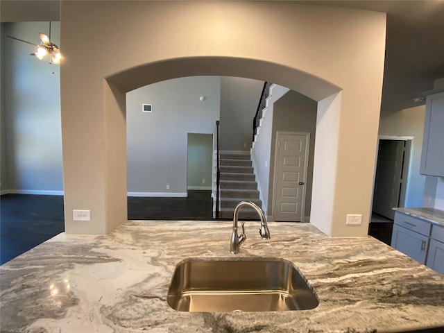 kitchen with light stone counters, arched walkways, visible vents, and a sink