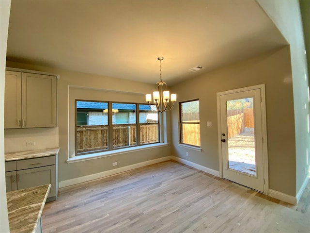 unfurnished dining area featuring an inviting chandelier and light hardwood / wood-style floors