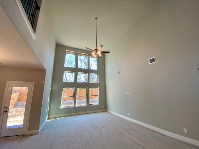 interior space featuring ceiling fan, light hardwood / wood-style flooring, and a towering ceiling