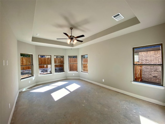 unfurnished room with ceiling fan, concrete flooring, and a raised ceiling