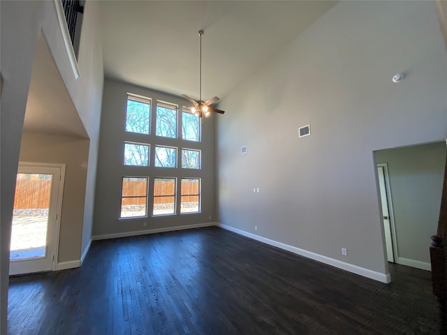 unfurnished room featuring a healthy amount of sunlight, visible vents, dark wood finished floors, and baseboards