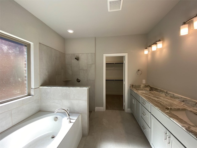 full bath with a garden tub, a sink, visible vents, a spacious closet, and a tile shower