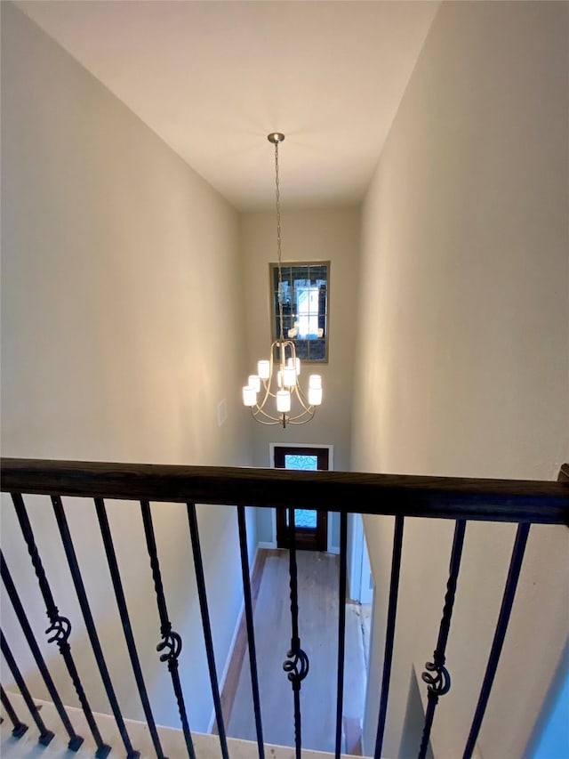 stairs featuring wood-type flooring and a chandelier