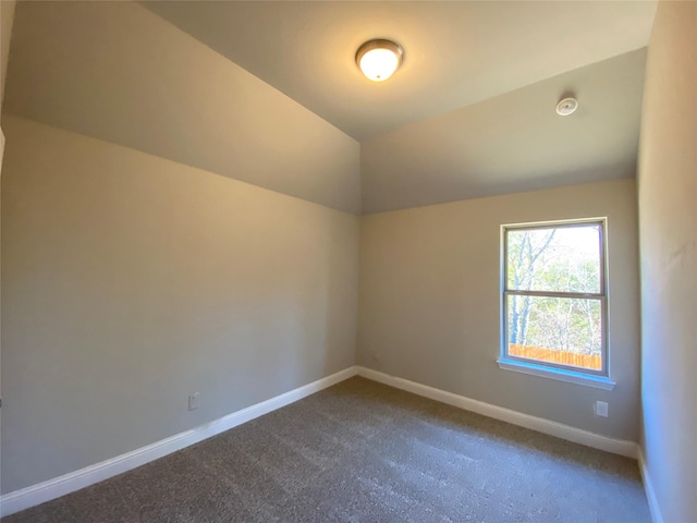 additional living space with baseboards, vaulted ceiling, and dark colored carpet