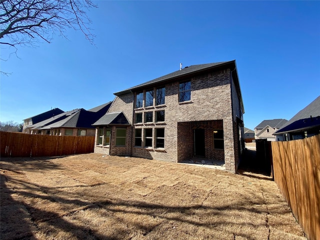 rear view of house featuring a fenced backyard and brick siding