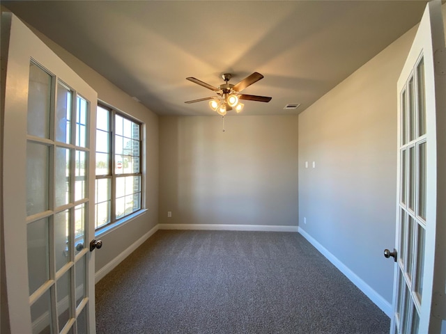 unfurnished room with french doors, visible vents, dark carpet, a ceiling fan, and baseboards