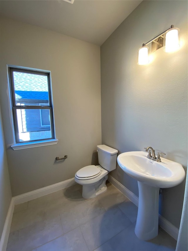 bathroom featuring baseboards, toilet, and tile patterned floors