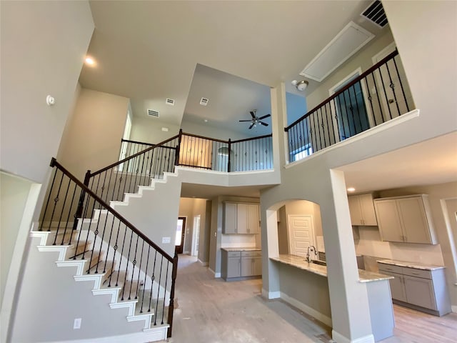 stairway with ceiling fan, a high ceiling, and wood-type flooring