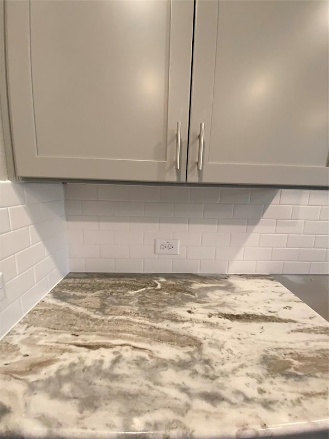 room details featuring dark stone counters, backsplash, and gray cabinetry