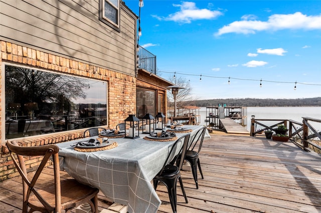 deck with outdoor dining space and a water view