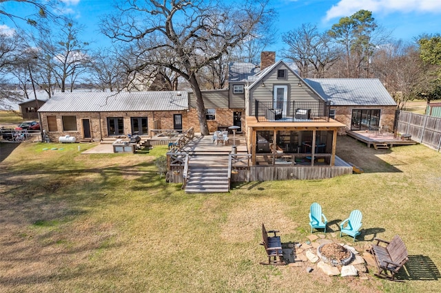 rear view of property featuring a lawn, a patio area, a deck, and a fire pit