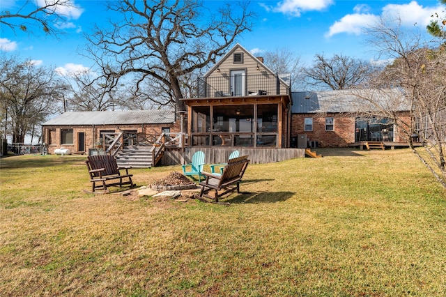 back of house with a sunroom, a fire pit, and a lawn