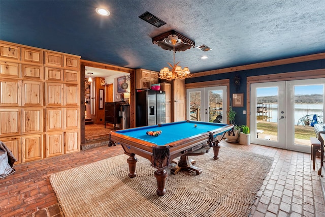 playroom featuring a textured ceiling, pool table, french doors, a healthy amount of sunlight, and a chandelier