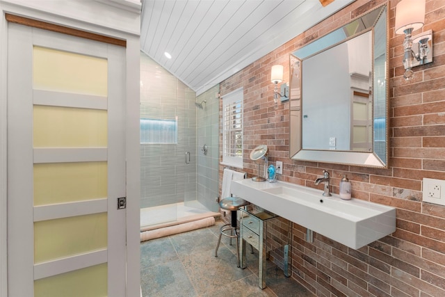 bathroom featuring a shower with shower door, sink, and lofted ceiling