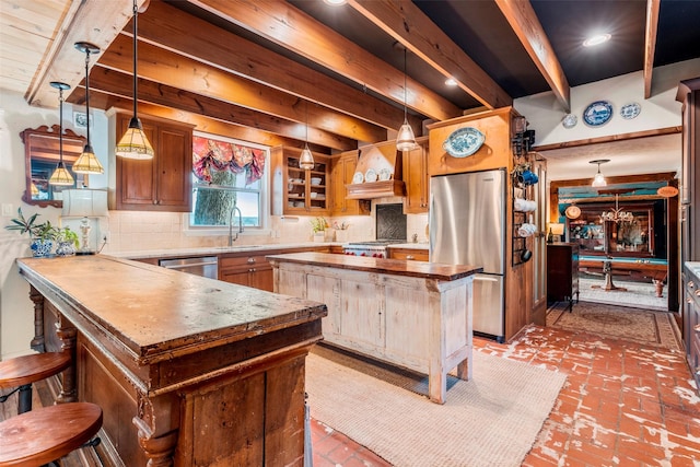 kitchen with stainless steel appliances, premium range hood, brick floor, beam ceiling, and tasteful backsplash