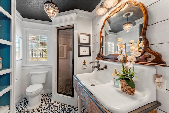 bathroom with toilet, an inviting chandelier, tile patterned flooring, and crown molding