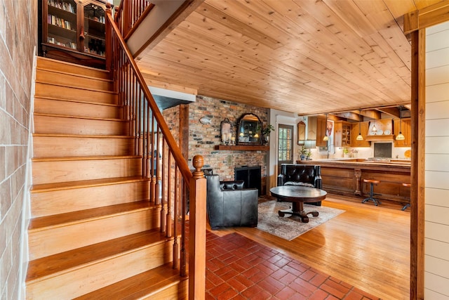 stairs featuring a brick fireplace, wooden ceiling, and wood walls