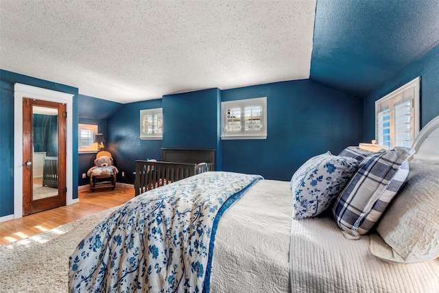 bedroom featuring lofted ceiling, multiple windows, a textured ceiling, and hardwood / wood-style flooring