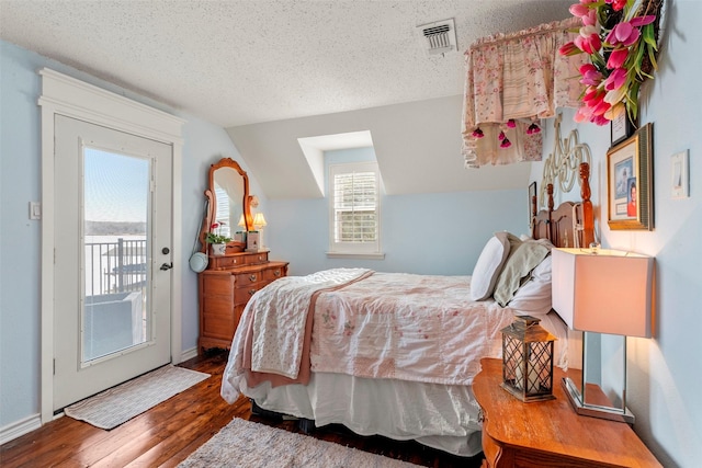 bedroom with a textured ceiling, access to exterior, vaulted ceiling, and hardwood / wood-style flooring