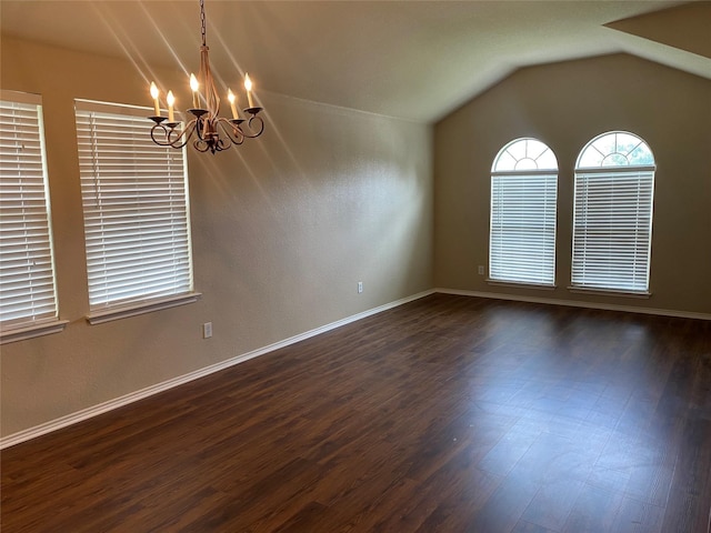 spare room featuring lofted ceiling, dark hardwood / wood-style flooring, and an inviting chandelier