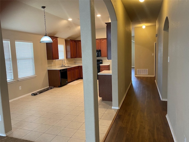 kitchen featuring light tile patterned floors, lofted ceiling, hanging light fixtures, black appliances, and sink