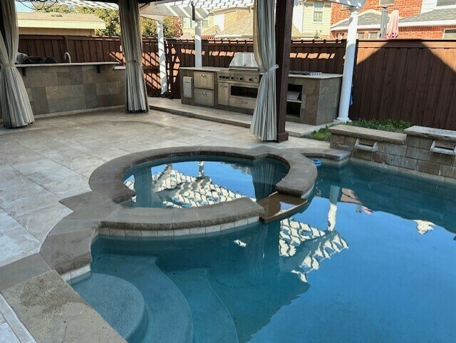 view of pool featuring a grill, an in ground hot tub, area for grilling, exterior bar, and a patio