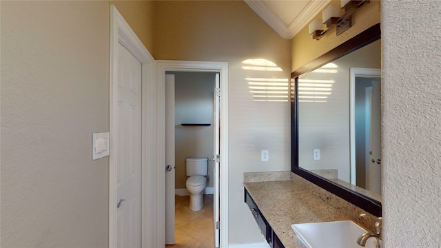 bathroom with toilet, vanity, tile patterned flooring, lofted ceiling, and crown molding