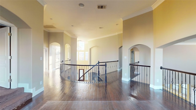 hall with dark hardwood / wood-style flooring, crown molding, and a towering ceiling