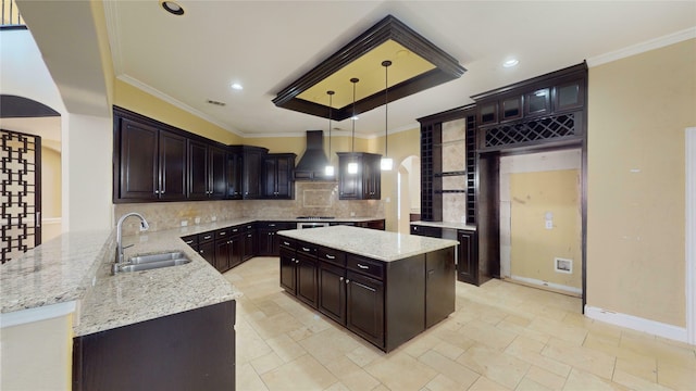 kitchen with sink, hanging light fixtures, kitchen peninsula, ornamental molding, and custom range hood