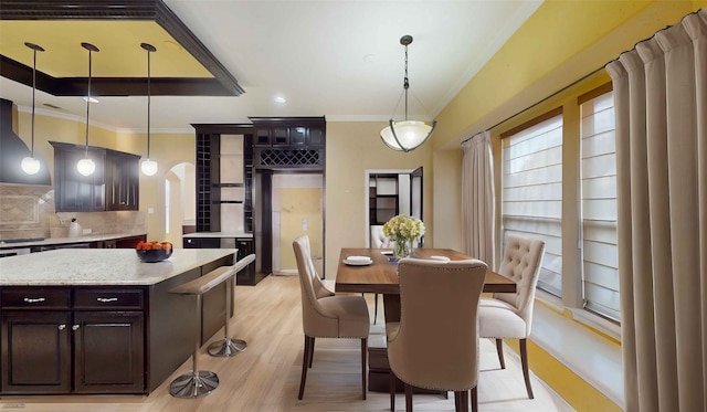 dining room featuring a raised ceiling, ornamental molding, and light hardwood / wood-style flooring