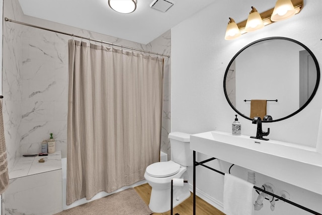 bathroom featuring toilet, hardwood / wood-style floors, and shower / tub combo with curtain